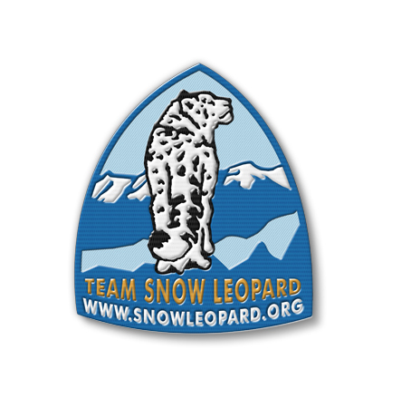 A blue embroidered triangular patch with a black and white snow leopard in the middle. Text says: Team Snow Leopard. www.snowleopard.org